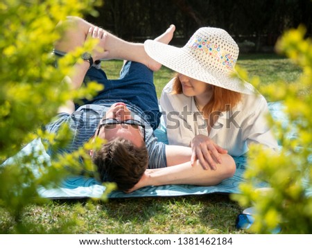 a pair of happy lovers resting on the grass with bare feet laughing and rejoicing