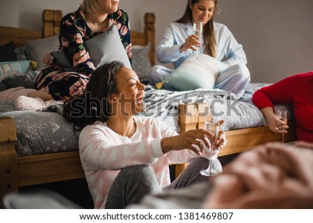Small group of female friends relaxing and talking while enjoying a girls night in. They are sitting in a bedroom in their pyjamas. Royalty-Free Stock Photo #1381469807