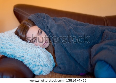 Sick woman with headache sitting under the blanket. Sick woman with seasonal infections, flu, allergy lying in bed. Sick woman covered with a blanket lying in bed with high fever and a flu, resting.