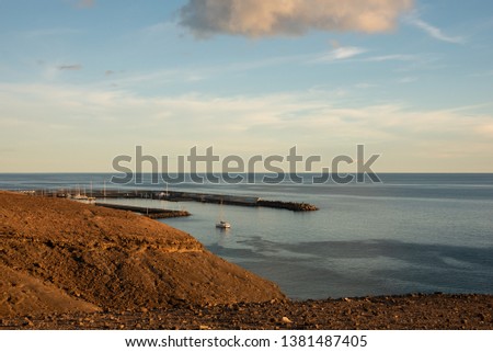 Sunset over Morro Jable harbor, Fuerteventura, Canary Islands, Spain. Pier, yachts and volcanic rocks. 
