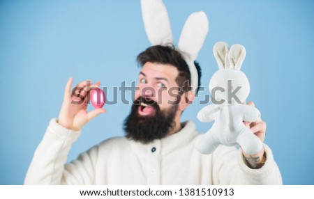 Look what i found. Hipster cute bunny blue background. Easter bunny. My precious. Funny bunny with beard and mustache hold pink egg. Easter symbol concept. Bearded man wear bunny ears. Egg hunt.