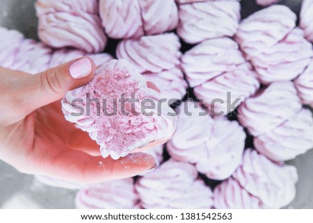 Close up woman's hands holds freshly prepared homemade marshmallow against a background of a lot ofmarshmallows. Natural marshmallows
