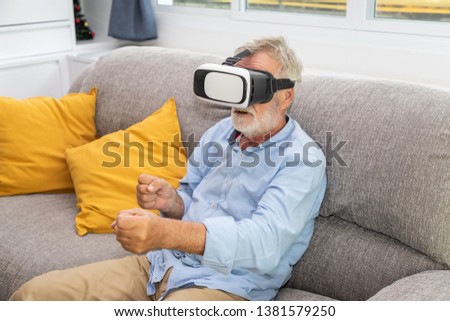 Senior old man eldery enjoy playing game with VR Virtual Reality goggle on couch sofa