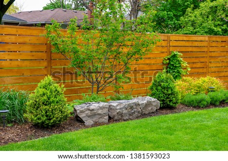 An Asian inspired and beautifully maintained garden features rockery and minimalist style cedar fencing. Royalty-Free Stock Photo #1381593023
