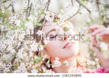 Spring portrait of a young blonde near a flowering tree. Happy young woman. Spring.