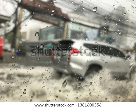 Raindrop on window of car. Soft picture of car driving in rain on flooded road. 