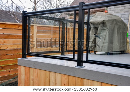 A newly constructed backyard deck uses wood composite, cedar skirting and glass and metal railings, while Asian inspired horizontal fencing helps complete the contemporary feel. Royalty-Free Stock Photo #1381602968