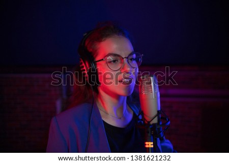 A young pretty woman in glasses singing in neon lighting