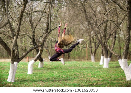Rhythmic gymnastics. Young gymnast girl jumping in park