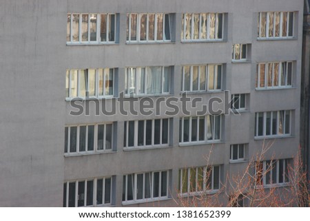 white plastic windows of an apartment building, symmetrical frames in a gray house. many rooms in one house. modern housing construction. old building