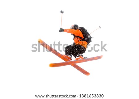 The athlete skier in the orange black suit does the jump trick by crossing the skis. real photo made in the mountains isolated on white background