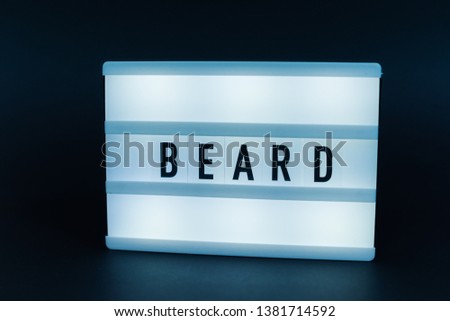 Photo of a light box with text, BEARD, over dark isolated 