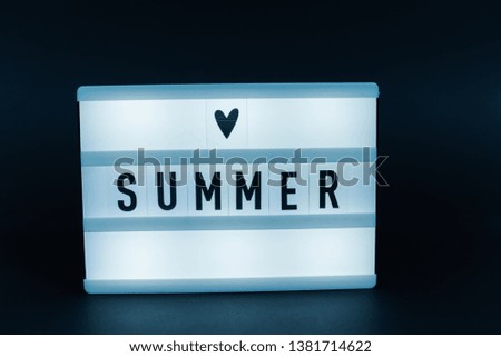 Photo of a light box with text, SUMMER, dark isolated background  