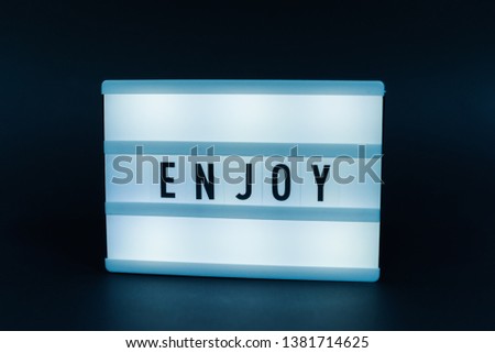 Photo of a light box with text, ENJOY, isolated background 