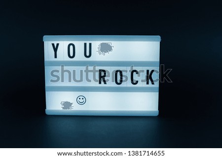 Photo of a light box with text, YOU ROCK, dark isolated background