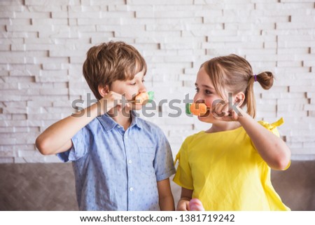 Adorable girl and boy holding colorful sweet meringues on a stick on Easter day