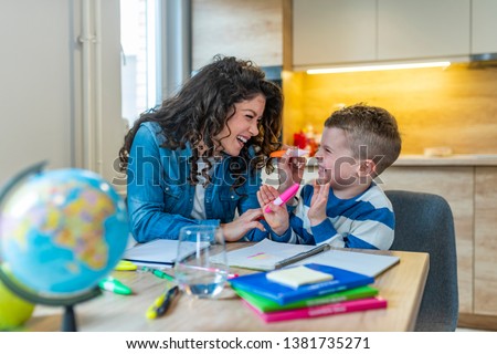 Mother helping with homework to her son indoor. Family, children and happy people concept. Mother and sons drawing together, mom helping with homework
