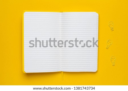 Notebook with blank pages and paperclip light bulb idea on yellow background