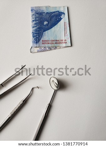 dentist utensils for oral review and argentine banknote of 200 pesos 
