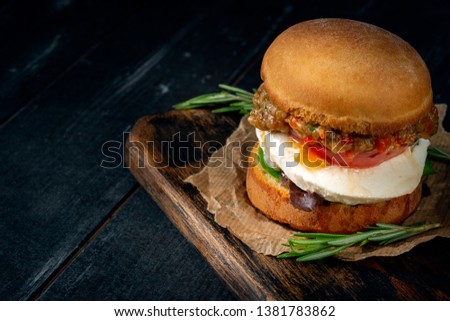 Homemade vegetarian Burger with mozzarella and fried eggplant on a wooden Board on a dark background. Healthy and proper nutrition, rustic style