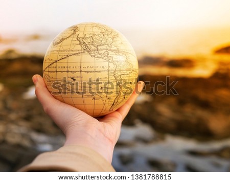Vacation travel summer weekend sea adventure trip concept. Vintage antique globe in hand on sea and rocks background. Copy space. Mock up for turism agency. Safe planet. Education and discovery idea Royalty-Free Stock Photo #1381788815