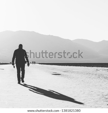 Man walking with strong shadow over salt. Black an white picture