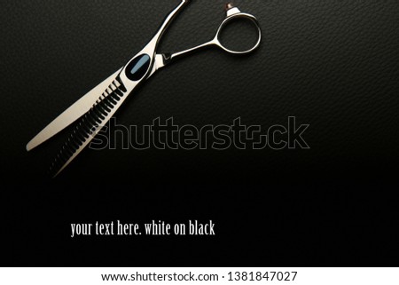 thinning scissors in the top corner on black background with copy space. dark blank for business card or website hairdresser.