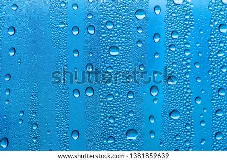 Raindrops on blue glass, background. The texture of water on the glass.