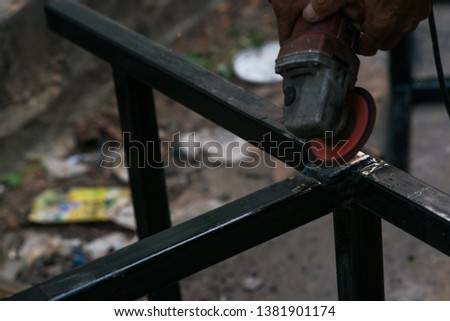 A worker cuts a piece of iron with a power tool. 