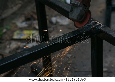 A worker cuts a piece of iron with a power tool. 