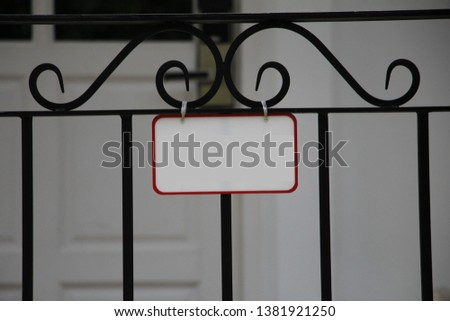 a white label hanging at the fence in front of the house 