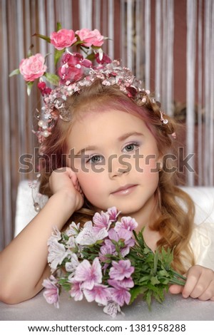 little girl in a flower crown with a bouquet of flowers, portrait sitting at a table