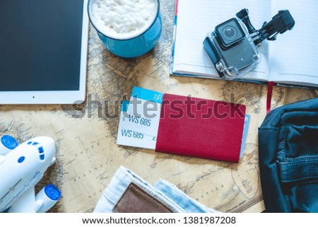 Airline tickets, passport, camera, tablet, jeans, plane and map on the table. The view from the top. Gathering for a trip or travel to meet adventures.