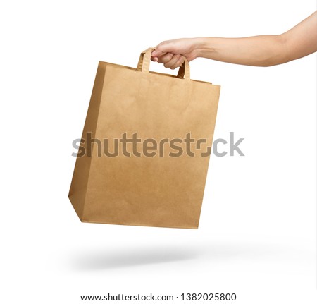 Right hand holding a brown paper bag with handle isolated on white  Royalty-Free Stock Photo #1382025800