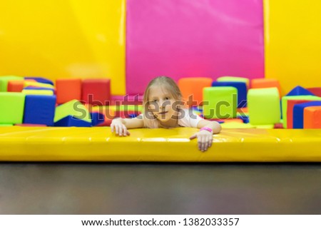 Little girl in the play area with soft cubes trying to climb out
