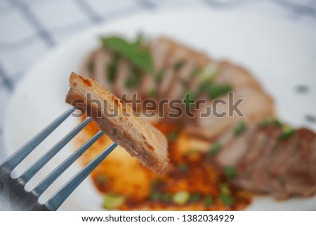 Grilled pork with Thai spicy dipping sauce is placed in a white dish with modern patterned tablecloths. Selection a part of picture for zoom.