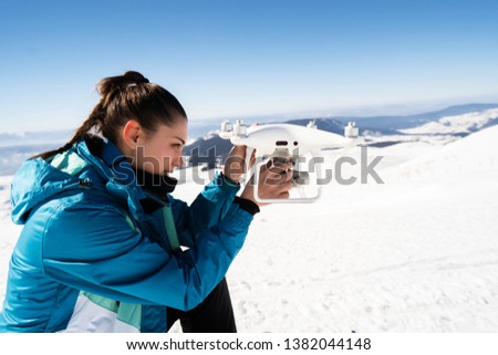 drone flying at winter snowy forest piloted by young woman - Image