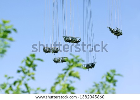 Chain carousel against the blue sky. The blurred trees in the background. Parks and entertainment concept.