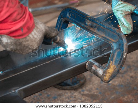 Worker is weld metal with a arc welding machine at the construction site. blue sparks fly to the sides. Industrial steel welder in factory technical. welder Industrial in factory