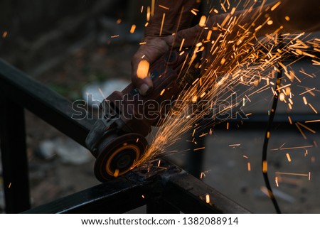 A worker cuts a piece of iron with a power tool.