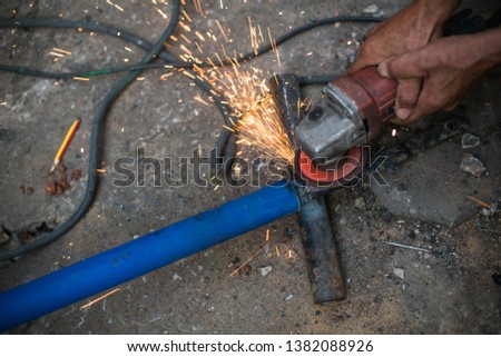 A worker cuts a piece of iron with a power tool.