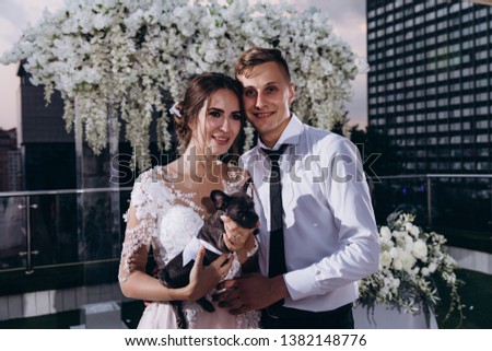 Newlyweds congratulate each other. The dog in the arms of the bride.
