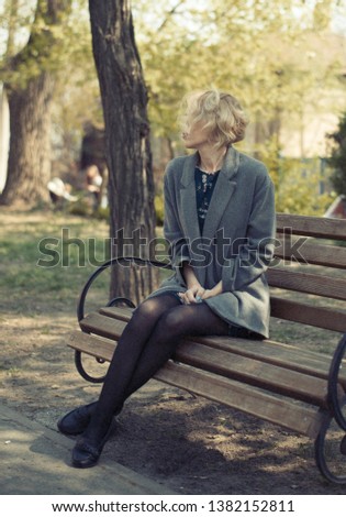 woman in a gray coat on a park bench