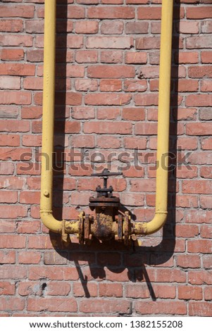 valve, the valve is old, rusty is connected to the gas pipes on a brick wall