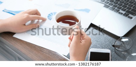 Business concept. Woman reading reports and drinking for rest in office table. Backlighting, sun glare effect, close up, side view, copy space
