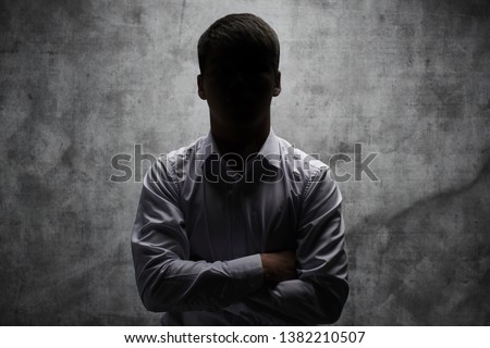 Anonymous man in a business shirt with arms crossed against a dark background Royalty-Free Stock Photo #1382210507