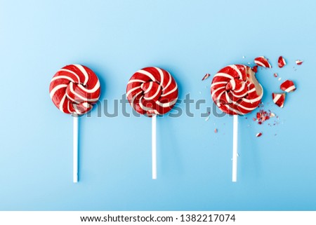 Crushed colorful candy lollipop on blue background. Colored lollipop on a blue background.Color candy on a blue background.Red and white spirals on lollipop. Flat lay. Royalty-Free Stock Photo #1382217074