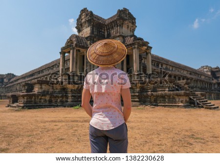 Woman in bamboo conical rice paddy hat in front of Angkor Wat temple in Cambodia