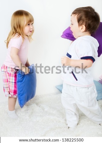 little boy and girl playing with pillows on bed