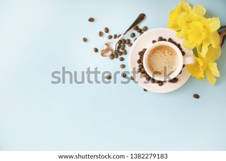 Cup of coffee and flowers on blue background
